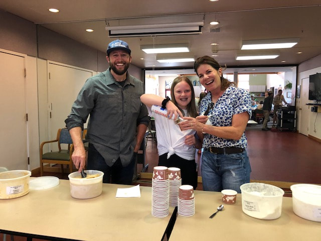 three volunteers scoop ice cream indoors