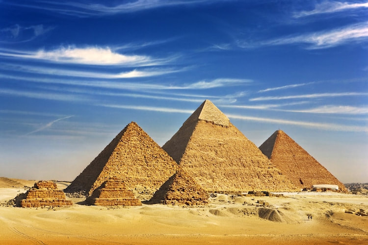 the pyramids of egypt with a blue sky and swirly clouds 