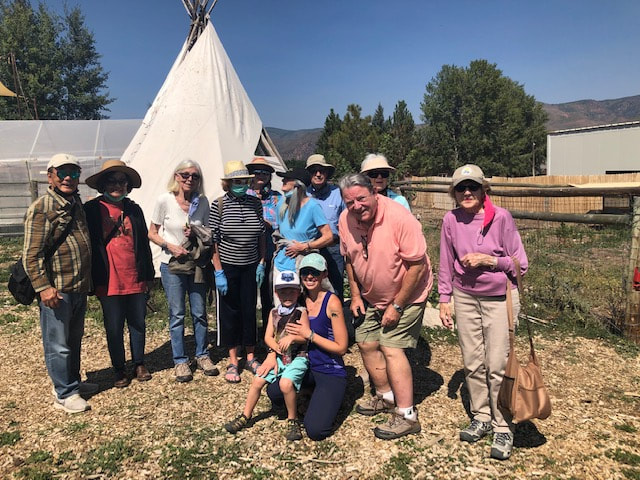 A group poses in front of a tepee at the farm collaborative